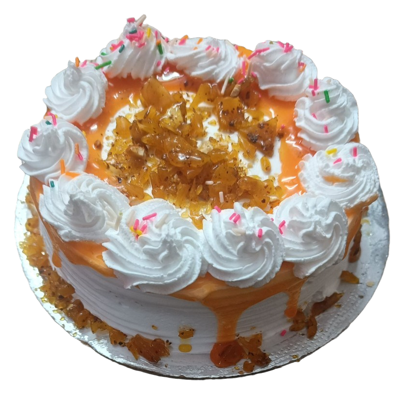 A round white cake with golden-coloured drips, white piped swirls, sprinkles and amber-coloured pieces on top.