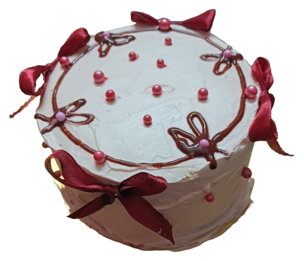 A white-frosted round cake decorated with burgundy bows, pink pearl shapes and piped loops.